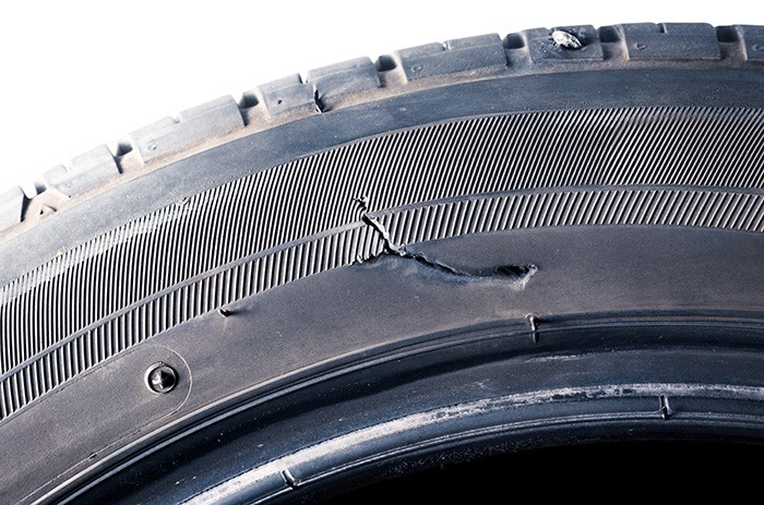 The car tires have a tear on the sidewall and a nail stabbing at Un pneu de voiture avec une déchirure sur le flanc et un clou planté dans la périphérie.