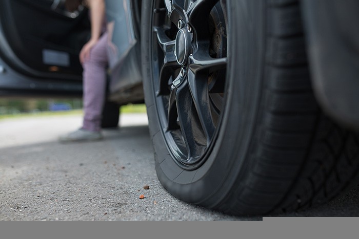 Woman with car broken down, flat tire gros plan d'un pneu dégonflé