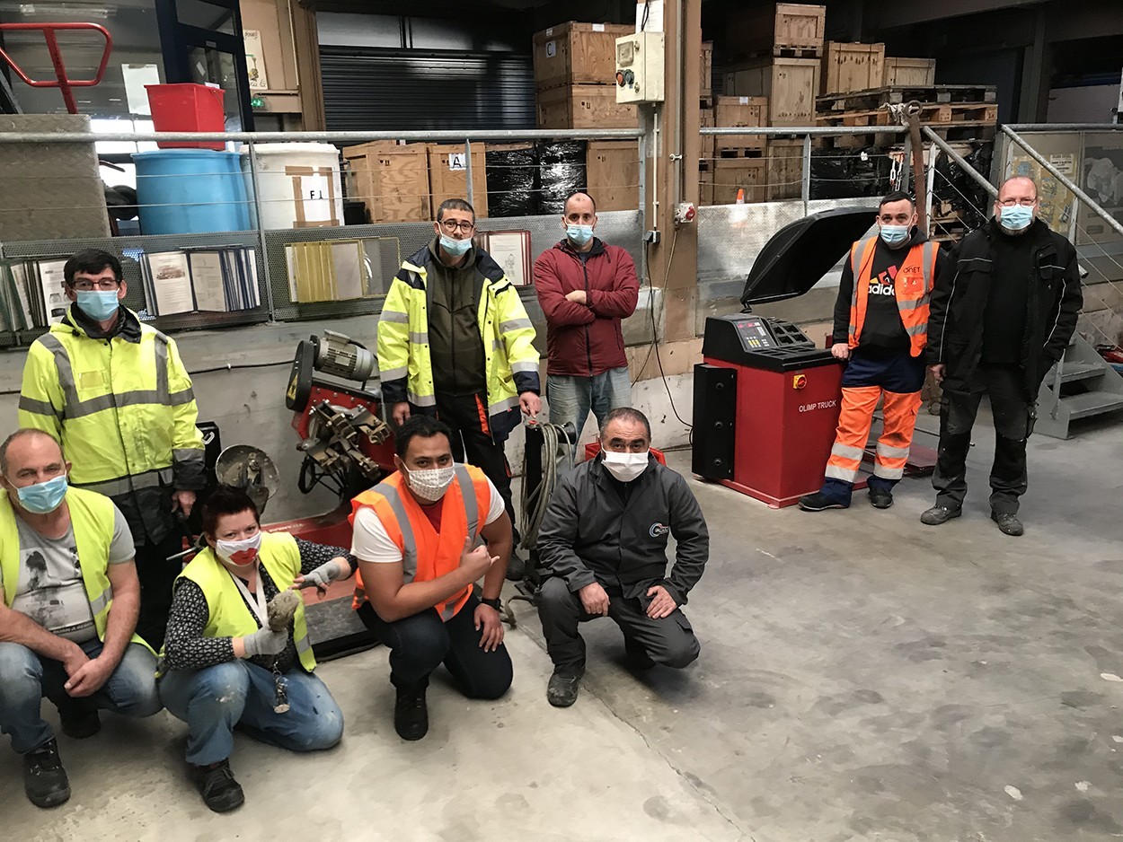 atelier-de-formation-pneumatique Plusieurs personnes en tenues de sécurité pose pour une photo au sein d'un atelier.
